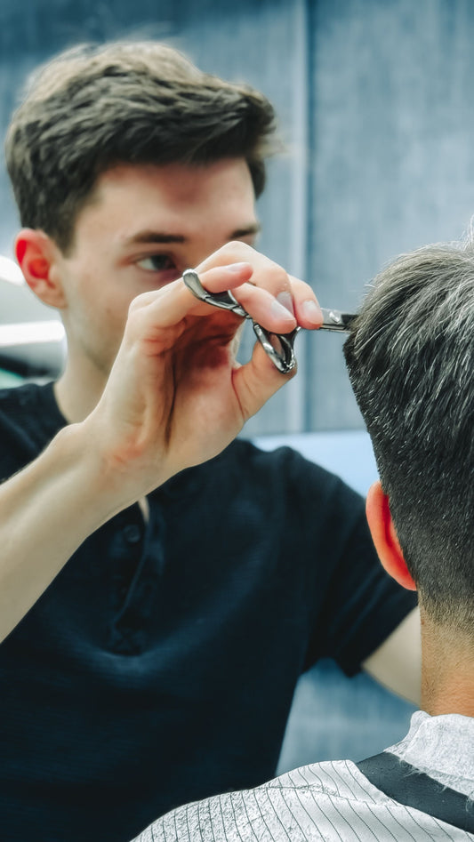 Parrucchiere che taglia le punte dei capelli con le forbici